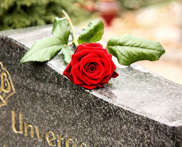Eine rote Rose auf einem Grabstein